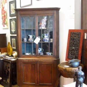 George III oak standing corner cupboard, having a shaped cornice above two slightly gothic style glass moulded doors