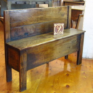 A 19th Century French 'banc de foyer' having a solid panelled back and a box seat support on stile feet