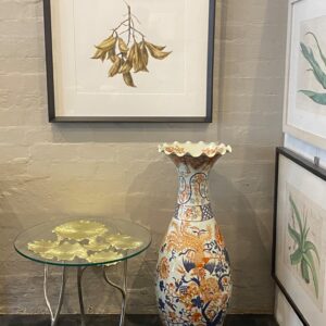 A decorative glass top occasional table, with golden toned cast iron lotus leaves.