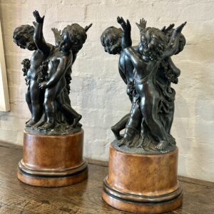 A charming pair of Italian bronzed Renaissance-style putti figures, each supporting a beautifully turned burr elm urn.